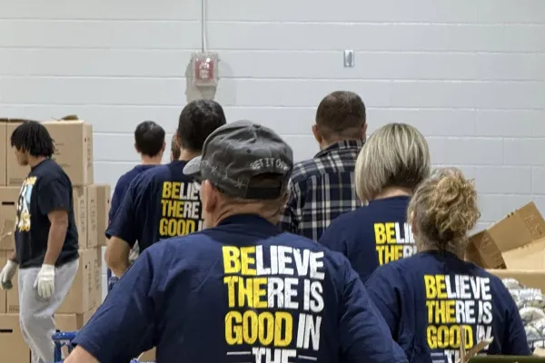 A photo at the Central Ohio CLC's annual Christmas Cares, Union Shares Event, with a man pushing a shopping cart wearing a shirt saying "Believe There is Good In The World"