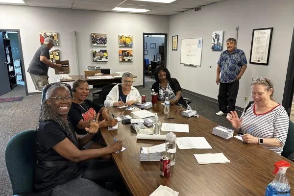 Table of five people sitting at a tale at a postcard writing party